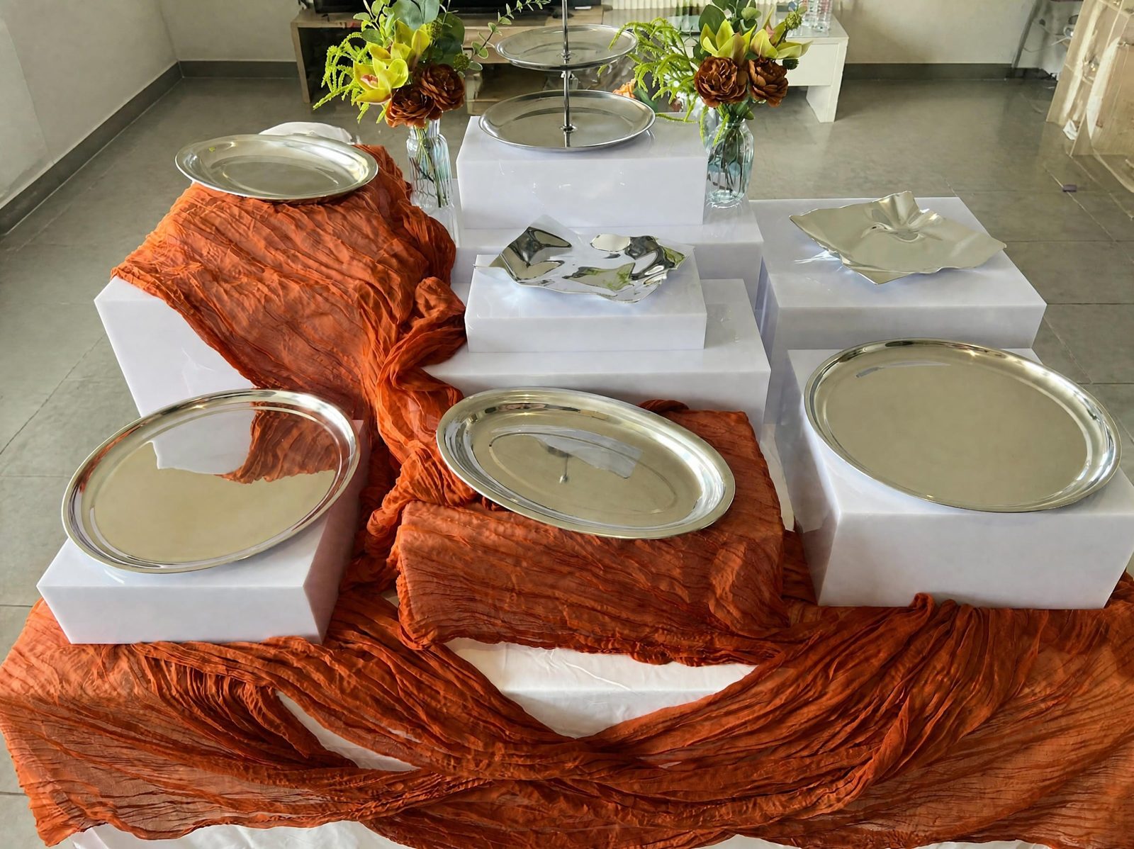 Cubes blancs, plateaux argentés et drapé terracotta installés pour un buffet à Toulouse
